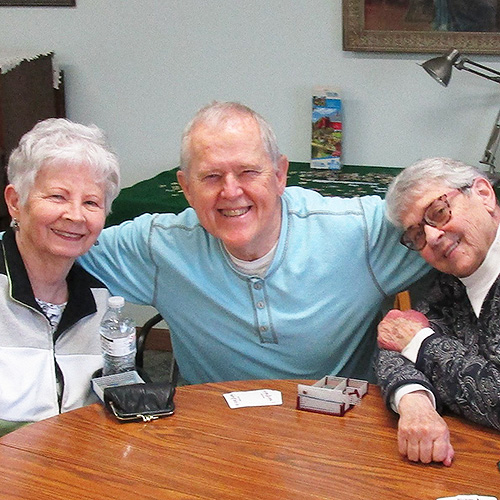 Three people with playing cards and card shuffler